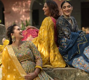 Three beautiful women sitting together wearing latest Anarkali Suits by Kalki Fashion pictured on an outdoor location