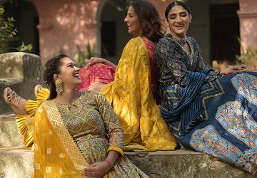Three beautiful women sitting together wearing latest Anarkali Suits by Kalki Fashion pictured on an outdoor location