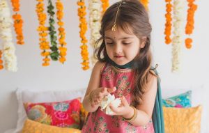 A small girl wearing ethnic dress playing with flowers looking cool and comfortable