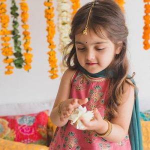 A small girl wearing ethnic dress playing with flowers looking cool and comfortable