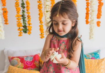 A small girl wearing ethnic dress playing with flowers looking cool and comfortable